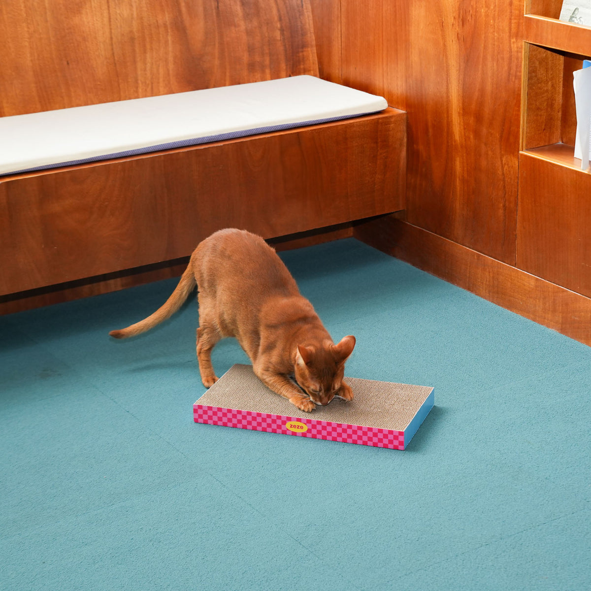 zeze Neon Sweetheart cardboard cat scratcher pad, cat scratching the pad in a wood-panelled room