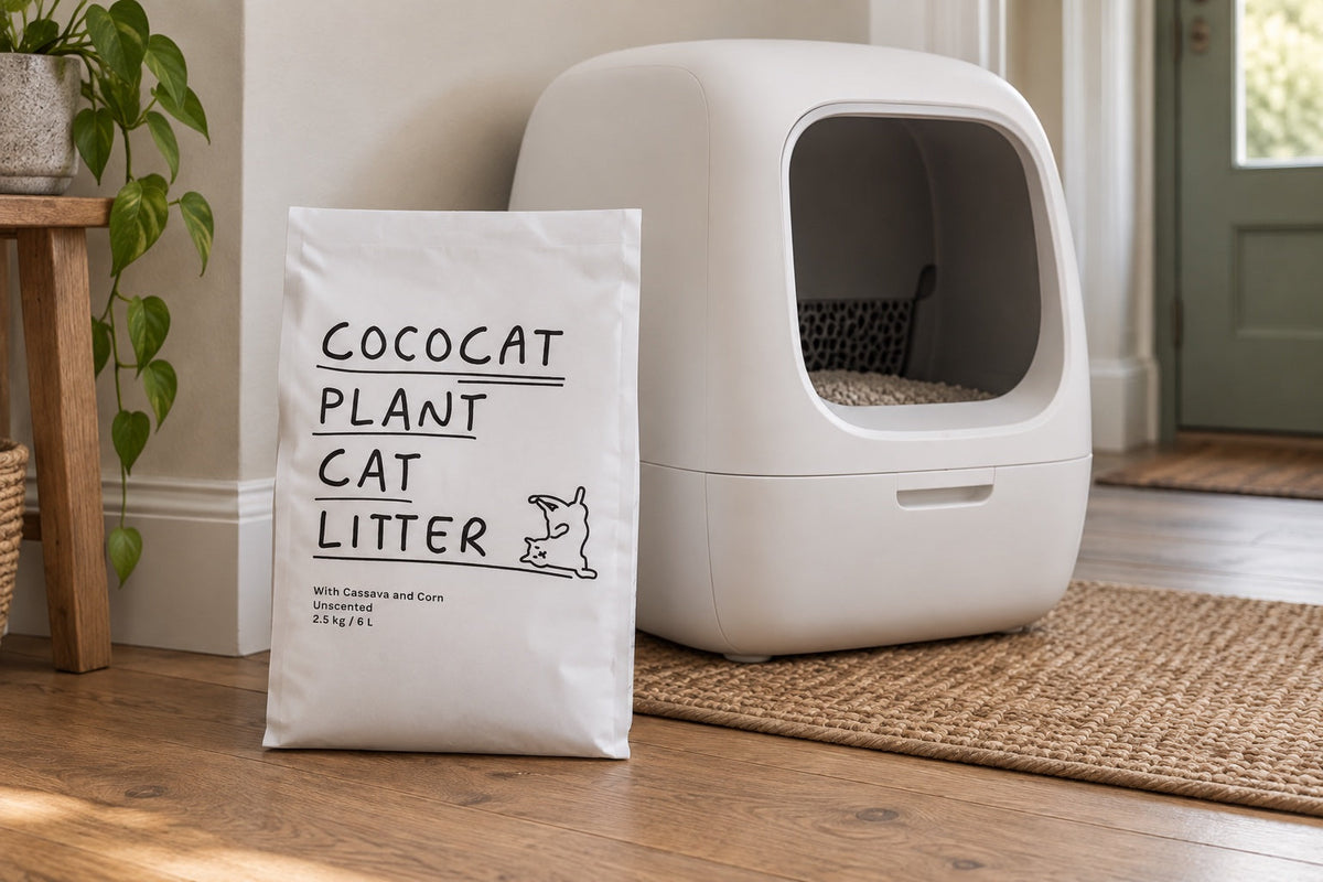 A bag of CocoCat cassava cat litter beside an automatic litter box in a hallway.